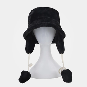 Detail of winter faux fur bucket hat with earflaps and plush pompom chin straps