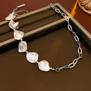 Détail d'un collier chaîne argentée avec éclats de nacre irréguliers sur écrin à bijoux