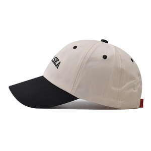 Side view of two-tone cotton baseball cap with bold black Alaska embroidery on cream crown