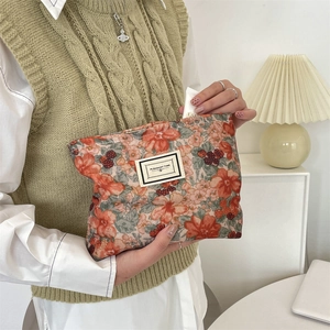 Detail of floral corduroy makeup bag held by hand in a retro aesthetic lifestyle setting