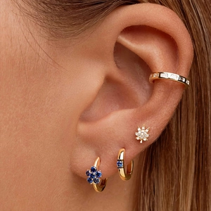 Close-up of gold ear cuff and stud earring set with blue and clear gemstones