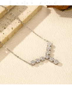 Detail of silver Y-shaped floral necklace with sparkling zircons on textured background