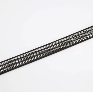 Detail of black leather punk belt with three rows of silver square pyramid metal studs