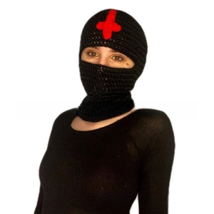 Detail of handmade black knitted balaclava featuring a red embroidered cross emblem