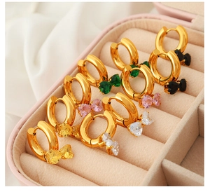 Close-up of five pairs of gold hoop earrings with colorful bow-shaped zircon stones