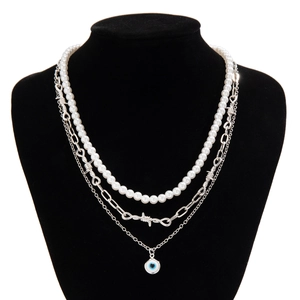 Detailed close-up of a three-layer necklace featuring pearls, barbed wire chain and evil eye