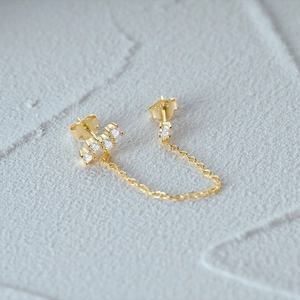 Detailed macro view of S925 sterling silver stamp on gold chain drop earrings with zircons