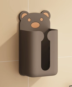 Detail of cute dark brown bear wall-mounted tissue box holder on bathroom tiles