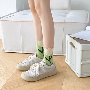 Detail of light green cotton socks with white tulip patterns worn with platform sneakers