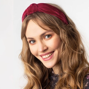 Close-up of deep red velvet knotted headband texture worn by a model in studio
