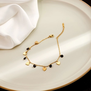 Detailed close-up of golden heart charms and black beads on an elegant bracelet