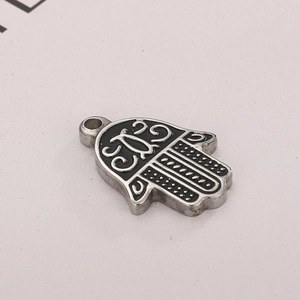 Macro view of silver stainless steel hand pendant with intricate black engraved patterns