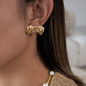 Détail de boucles d'oreilles nœud dorées avec texture lave sur un mannequin femme