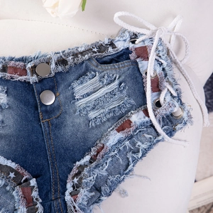 Dettaglio di pantaloncini in denim a vita bassa con lacci laterali e nastro a stelle