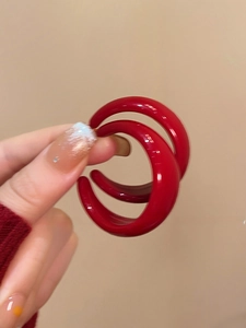 Gros plan sur les boucles d'oreilles créoles C rouges en acrylique avec fini brillant poli