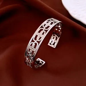 Silver hollow cuff bracelet with cutout letters on luxury red silk background
