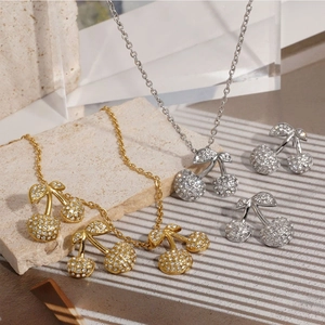 Elegant crystal-studded cherry jewelry set including gold and silver necklaces and earrings