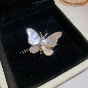Macro detail of 14K gold plated butterfly brooch with mother of pearl and zircon