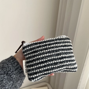 Close-up of hand holding black and white striped woven coin purse with simple wish label