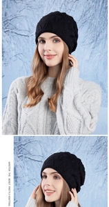 Detail of a black knitted beret with beaded accents shown in a snowy winter setting