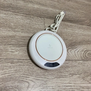 Top view of a white electric mug warmer with rose gold trim and USB cable on wood