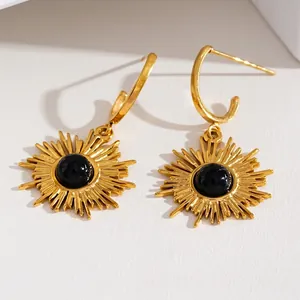 18K gold plated sun pendant earrings with black natural stone on textured background