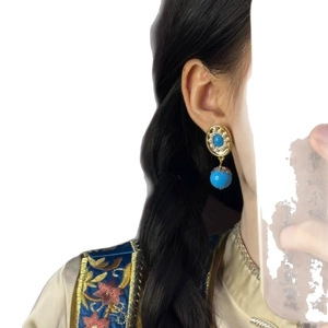 Vintage style gold and blue turquoise stone earrings with small pearls on model