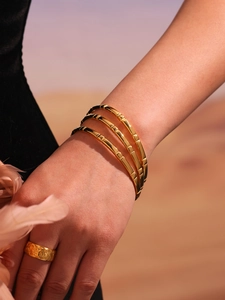 Detail of 18k gold plated stainless steel bangles with bamboo texture and hammered ring