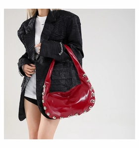 Detail of red oil wax leather hobo bag with silver rivet accents and glossy finish