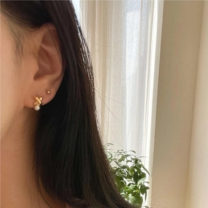 Elegant 925 sterling silver gold-plated pearl stud earrings worn by a model in soft light