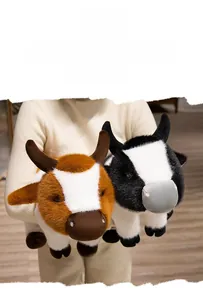 Detail of plush cow toys in brown and black spots held by a model in a cozy indoor setting