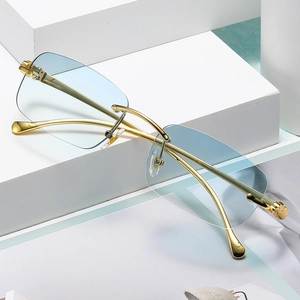 Detalle de gafas de sol cuadradas sin montura con cristales degradados azul claro y patillas oro