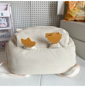 Detail of cream corduroy backpack featuring 3D duck feet decor and a stylish leather patch
