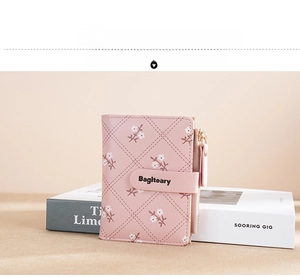 Close-up of pink women's short wallet with white floral print and zip pocket detail