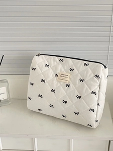 Quilted white cosmetic bag with black bow print and zipper closure for large capacity storage