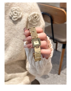 Gros plan d'une montre carrée dorée vintage avec boîtier minimaliste et bracelet métallique