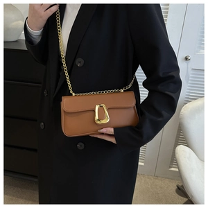 Detail of a brown leather crossbody bag featuring a golden chain strap and metallic closure