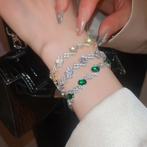 Detailed view of zircon buckle bracelets in gold and silver on a woman wrist