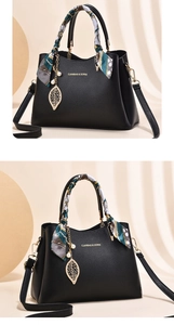 Detail of black leather handbag featuring silk scarf handle and golden leaf pearl charm