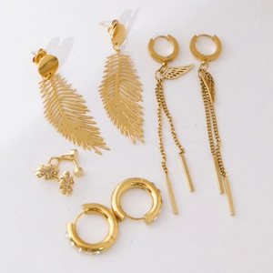 Collection of gold-plated titanium steel leaf and wing earrings on white background