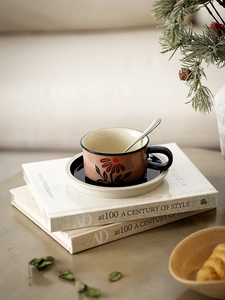 Close-up of vintage ceramic coffee cup with hand-painted floral motifs on a black saucer
