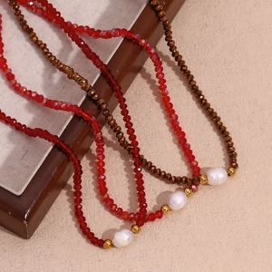 Detail of beaded necklaces with red faceted crystals, white pearls and gold accents