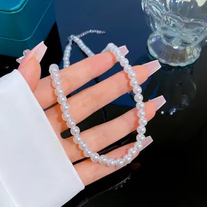 Elegant white round pearl necklace with metallic clasp held against a premium teal jewelry box