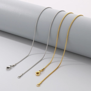 Detail view of minimalist gold and silver stainless steel box chains on display stand