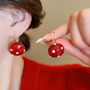 Detailed close-up of a red and white polka dot earring with a gold-plated finish on ear