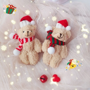 Detail of two beige plush bears wearing Christmas hats and scarves on mesh background