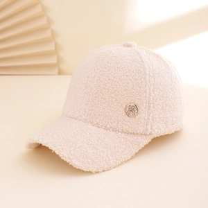 Close-up of beige lamb wool baseball cap featuring a decorative metal 'R' letter emblem