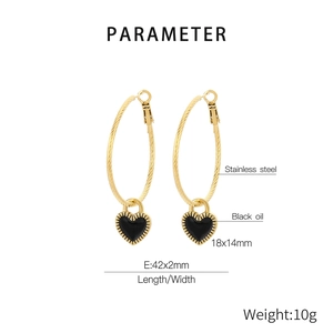 Detailed view of large gold stainless steel hoop earrings with black enamel heart charm