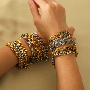 Macro shot of layered 18K gold plated chunky Cuban and Figaro chains on female wrist