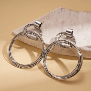 Macro shot of silver layered geometric hoop earrings resting on a textured stone base
